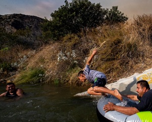 Eddie Lopez and his son, Eddie Jr. frolic near a drainage pipe along the San Gabriel River, in California, during the recent heat wave. PHOTOGRAPH BY ROBERT GAUTHIER, LOS ANGELES TIMES/GETTY IMAGES