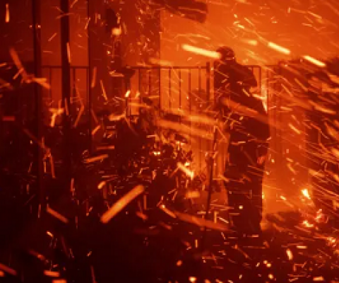 A man uses a garden hose to try to save his home from wildfire in Granada Hills, California, on 11 October 2019. Photograph: Michael Owen Baker/AP