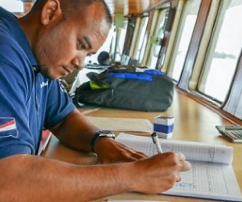 Fisheries officer Beau Bigler crosschecks ship documentation as a fishing vessel seeks authorisation to use the port of Majuro. Photo: Francisco Blaha.